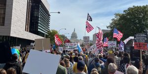People march toward the U.S. Capitol building down Pennsylvania Avenue waiving signs and American flags as part of the No Kings protests on October 18, 2025; Credit: Robert Beets